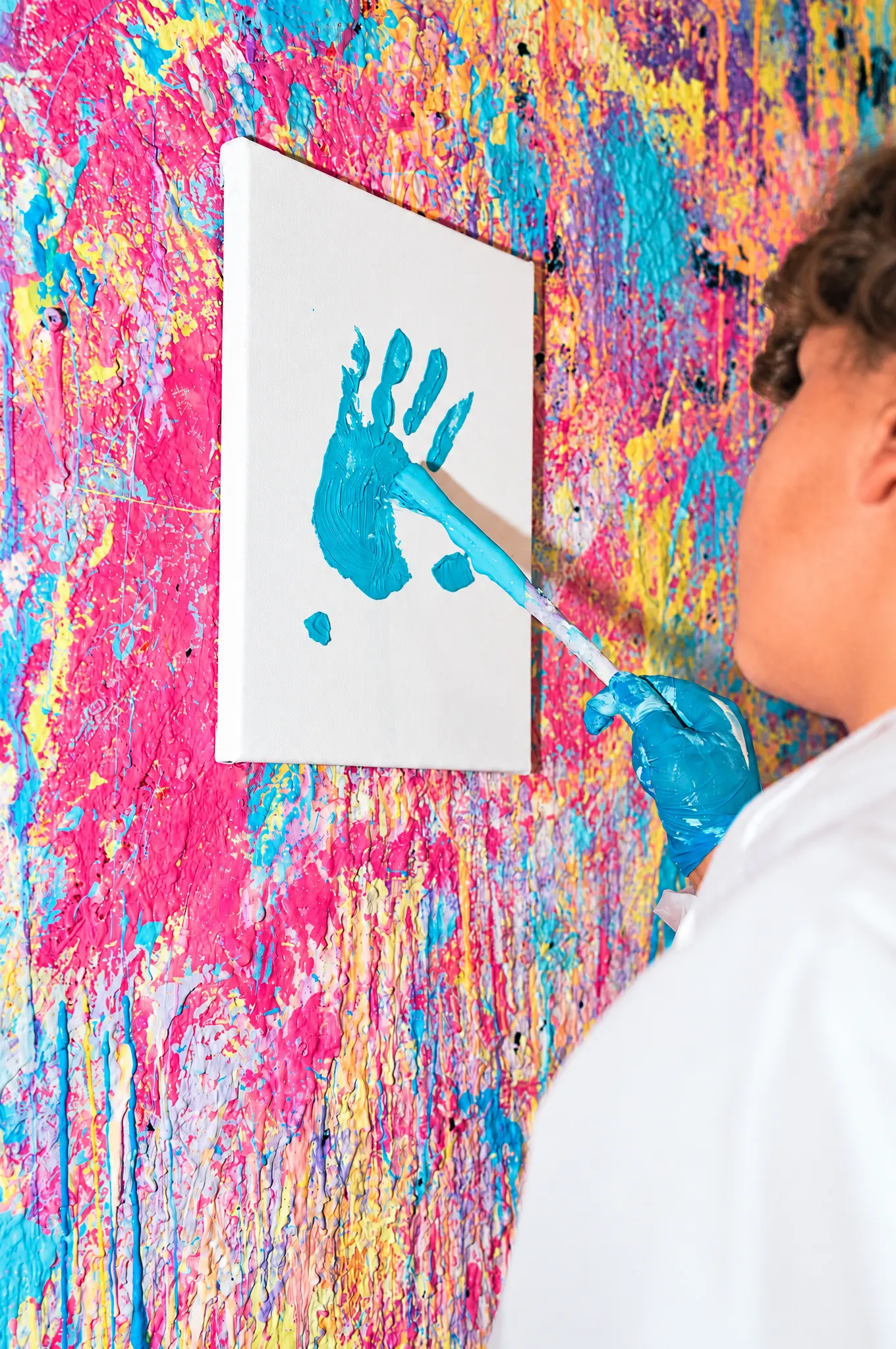 Kind drückt seine blaue Hand auf eine Leinwand