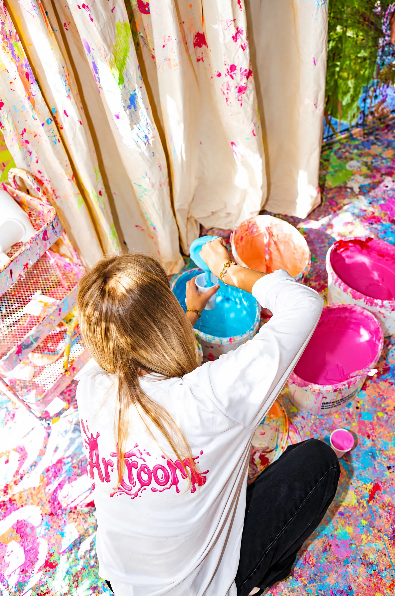 Mädchen im Artroom-Shirt zwischen Farbschalen