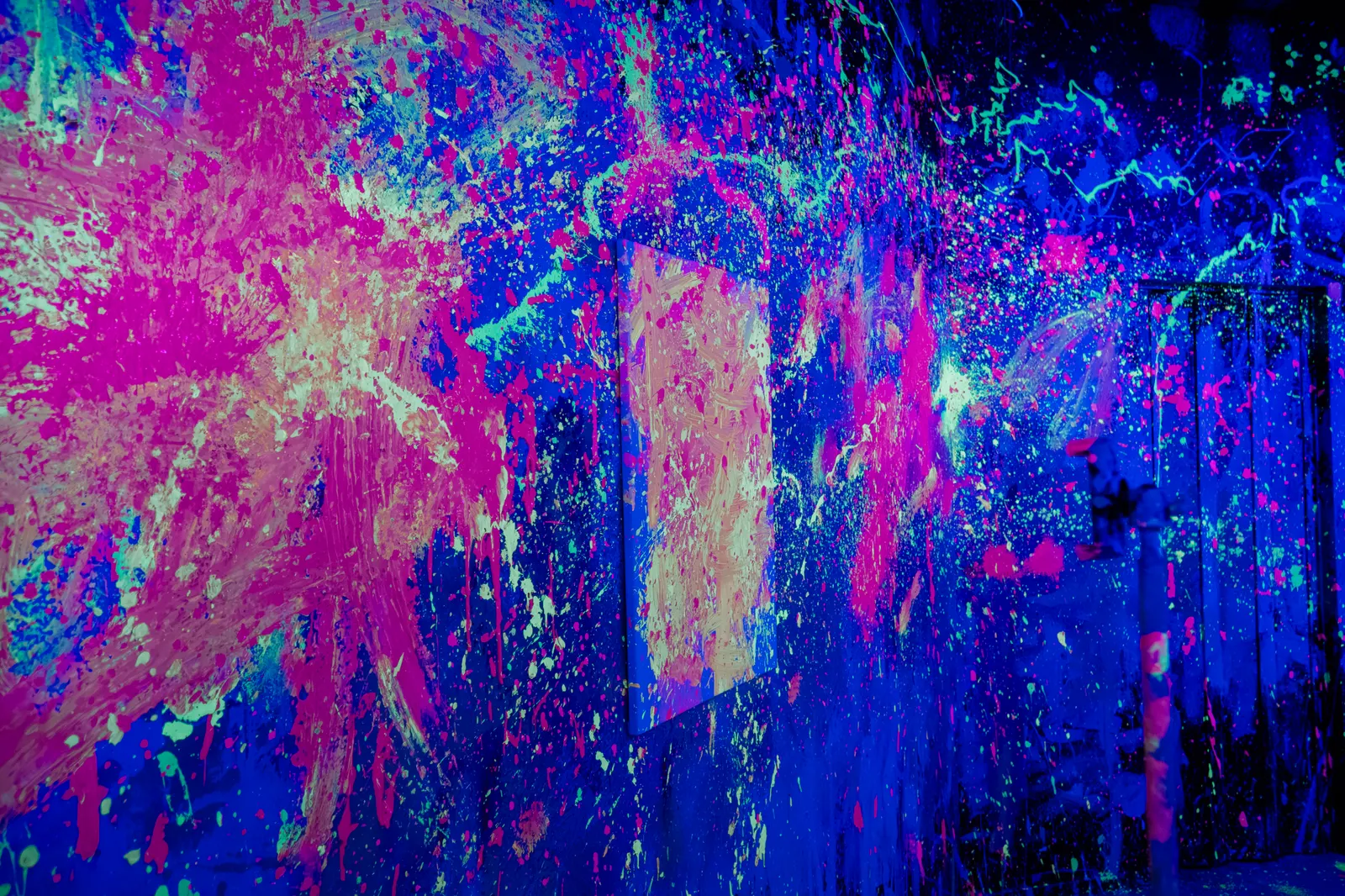 Wand voller leuchtender Neonfarbe im Schwarzlicht des Neon Rage Rooms